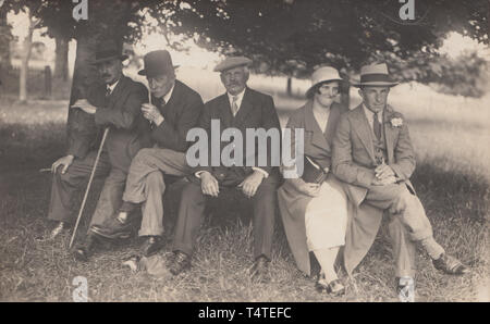 Vintage Cartolina fotografica che mostra un gruppo di cittadini britannici rilassante sotto un albero Foto Stock