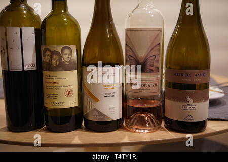 Vista ravvicinata di cinque bottiglie di vino greco, tra cui un rosé, allineate per una degustazione a una festa a Madrid Foto Stock