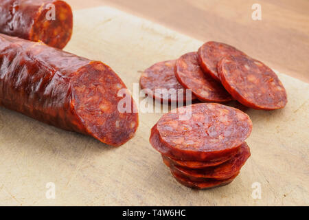 Chorizo iberico, il chorizo spagnolo spagnolo ​​or salsiccia tagliata a fettine su una tavola di legno. Piatto tipico spagnolo Foto Stock