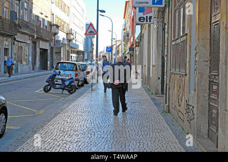 Anziani senior gentleman flaneur indossando un abito grigio passeggiando lungo Rua da Cedofeita guardando al quartiere Porto Portogallo KATHY DEWITT Foto Stock