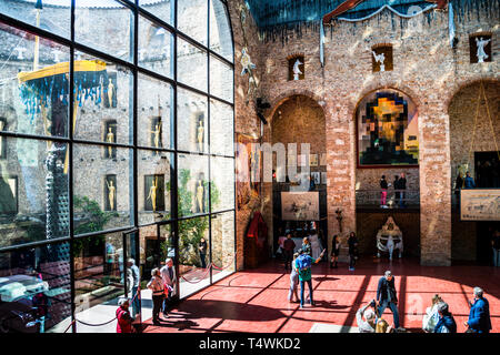 Attraverso la facciata in vetro della sala principale del Teatro-Museo Dalí a Figueres, in Spagna, si può vedere l'installazione "Taxi sotto la pioggia" nel cortile. I visitatori passeggiano sul pavimento in pietra rossa dell'ex palco, dove è sepolto Salvador Dalí. Foto Stock