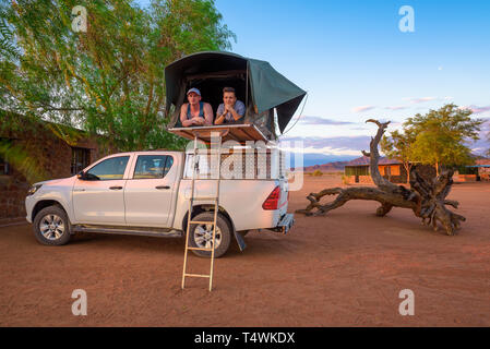 Coppia giovane giacente in una tenda che si trova sul tetto di un pickup 4x4 car Foto Stock