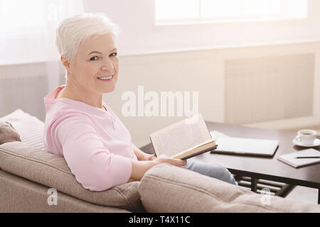 Elegante lady senior rilassante con libro preferito Foto Stock