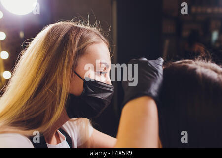 Cosmetologo rendendo le sopracciglia design. Donna attraente getting cura del viso a un salone di bellezza. Architettura perfetta delle sopracciglia. Foto Stock