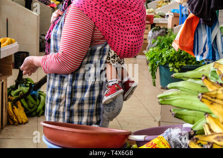 Una donna ecuadoriana con il suo bambino sulla schiena a livello locale mercato degli agricoltori Foto Stock