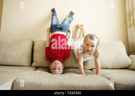Fratello e Sorella gioca sul lettino: il ragazzo sta a testa in giù Foto Stock