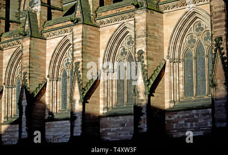 Vista parziale della parte esterna del medievale Lichfield Cathedral in Staffordshire (UK) che mostra quattro identiche finestre ad arco e contrafforti. Foto Stock