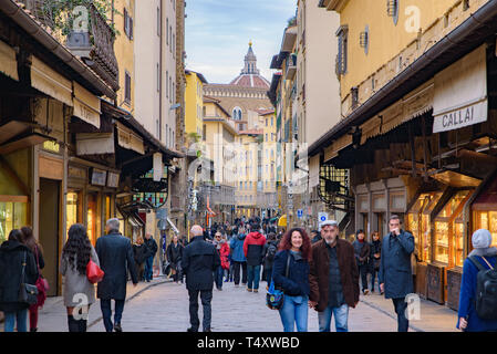 La gente che camminava sul Ponte Vecchio, un medievale ponte in pietra con negozi su di esso, Firenze, Italia Foto Stock