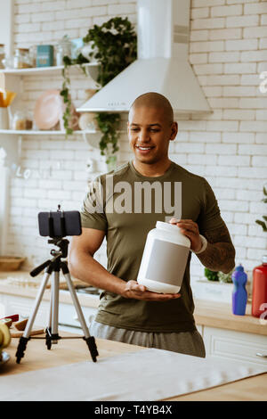 Uomo che indossa kaki shirt raccomandare una proteina per seguaci Foto Stock