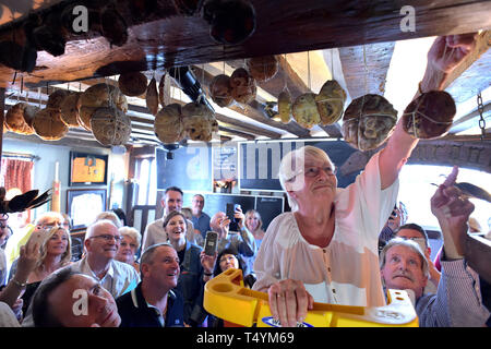 Pub dipendente Utteridge Margaret, 74, che ha lavorato presso la Bell Inn, High Road, Horndon-su-la collina, Essex dal 1984, pende un hot cross bun da una trave che è stata una tradizione presso la locanda sin dal 1906. Foto Stock