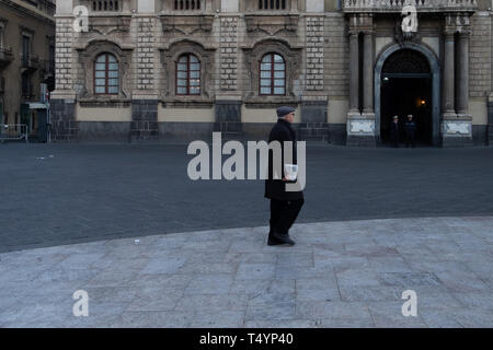 Sicilia, Italia - 21 Gennaio 2016: il vecchio uomo cammina con il giornale in mano a Piazzo Duomo di Catania. Foto Stock