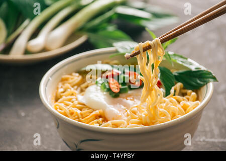 Chiuso fino tagliatelle istante con verdure su chopstick isolate su pietra dảk sfondo, cibo spazzatura o fast food concept. Foto Stock