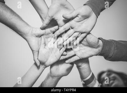 In prossimità dei giovani al lavoro di squadra di mettere le loro mani insieme per una nuova collaborazione - Allegro amici motivato su un piano Foto Stock