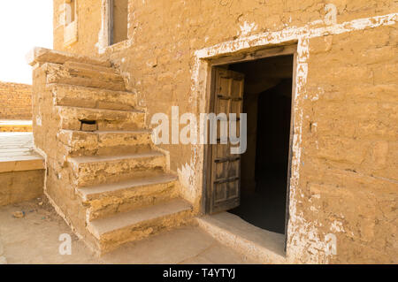 Gli edifici in pietra arenaria con scale e porte bassa in Kumbalgarh Jaisalmer Rajasthan, India. Questa famosa destinazione turistica è detto di essere ossessionato e a s Foto Stock