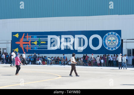 Bengaluru, India - 22 Febbraio 2019: i visitatori al Aero India 2019 resto dall ombra al di fuori della hall DRDO. Aero India è una biennale air show e Foto Stock