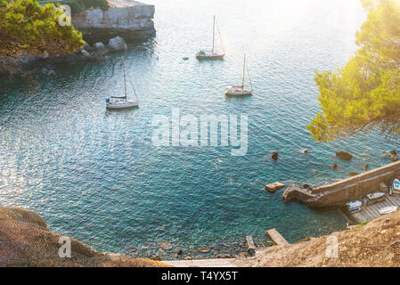 Alta ange vista delle barche a vela e nuoto di persone nella baia idilliaca sull isola di Maiorca su soleggiate giornate estive Foto Stock