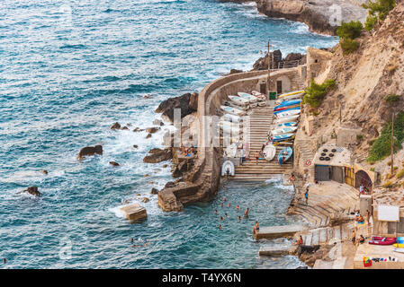 Banyalbufar, Mallorca, Spagna 08-10-2018: persone nuotare nel mare Mediterraneo vicino al piccolo porto con barche ormeggiate Foto Stock