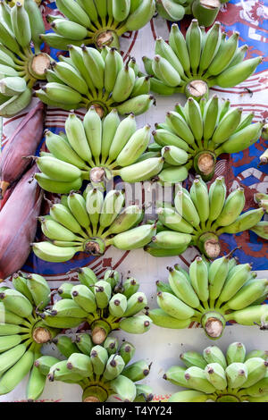 Molti banana acerba gettare sul tavolo per vendere, verticale Foto Stock