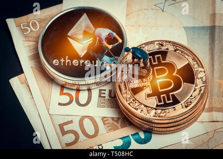 Macro miner figure lavorando sulla pila di bitcoin e ethereum poste sulle banconote in euro. virtuale moneta crypto minerario e concetto di trading Foto Stock