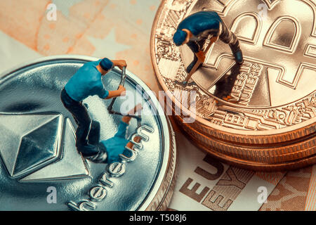 Macro miner figure lavorando sulla pila di bitcoin e ethereum poste sulle banconote in euro. virtuale moneta crypto minerario e concetto di trading Foto Stock