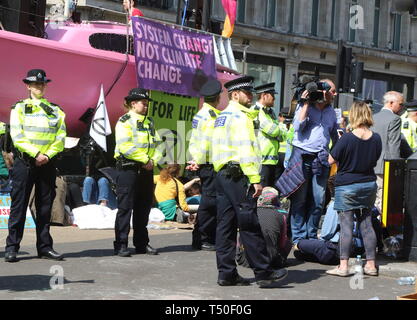 Londra, Regno Unito. Xix Apr, 2019. La polizia visto accanto ad una barca di rosa durante la dimostrazione.gli attivisti ambientali dalla ribellione di estinzione movimento occupare della Londra Oxford Circus per un quinto giorno. Gli attivisti parcheggiato una barca rosa nel mezzo della trafficata Oxford Circus road junction bloccando le strade e provocando il caos del traffico. Credito: Keith Mayhew/SOPA Immagini/ZUMA filo/Alamy Live News Foto Stock