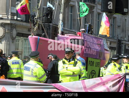 Londra, Regno Unito. Xix Apr, 2019. La polizia visto accanto ad una barca di rosa durante la dimostrazione.gli attivisti ambientali dalla ribellione di estinzione movimento occupare della Londra Oxford Circus per un quinto giorno. Gli attivisti parcheggiato una barca rosa nel mezzo della trafficata Oxford Circus road junction bloccando le strade e provocando il caos del traffico. Credito: Keith Mayhew/SOPA Immagini/ZUMA filo/Alamy Live News Foto Stock