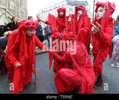 Gli artisti interpreti o esecutori visto in costumi di fantasia in mezzo alla folla durante la dimostrazione. Gli attivisti ambientali dalla ribellione di estinzione movimento occupare della Londra Oxford Circus per un quinto giorno. Gli attivisti parcheggiato una barca rosa nel mezzo della trafficata Oxford Circus road junction bloccando le strade e provocando il caos del traffico. Foto Stock