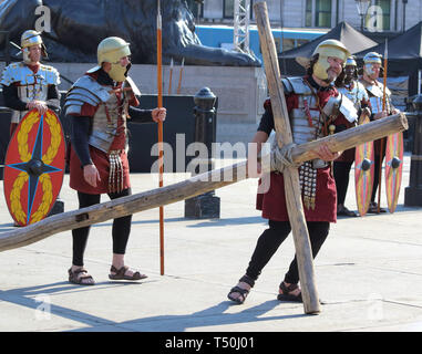 I soldati romani portare nel crocifisso durante una performance di 'La Passione di Gesù " da Wintershall giocatori in Trafalgar Square. Circa ventimila persone pranzo della Londra Trafalgar square per la performance annuale della Passione di Gesù mediante la Winterhall giocatori. La rievocazione della vita di Gesù dal suo arrivo a Gerusalemme per la sua crocifissione e resurrezione finale viene eseguita da un cast più di cento attori e volontari per gratis ogni Venerdì Santo. Foto Stock