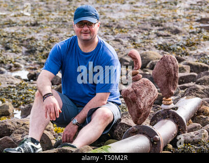 Dunbar, East Lothian, Scozia, Regno Unito, 20 aprile 2019. Unione di pietra campionato di impilamento: Dave amore, da Edimburgo, con pietre equilibrato a Eye Cave Beach Foto Stock