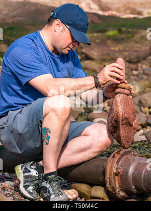 Dunbar, East Lothian, Scozia, Regno Unito, 20 aprile 2019. Unione di pietra campionato di impilamento: Dave amore, da Edimburgo, pietre di bilanciamento a Eye Cave Beach Foto Stock