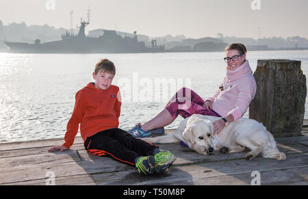 Passaggio, Cork, Irlanda. Xx Aprile, 2019. Donal McDonnell con sua madre Bláithín e il loro cane Liz rilassarsi in inizio di mattina di sole sul molo nel passaggio a ovest, Co. Cork, Irlanda. Credito: David Creedon/Alamy Live News Foto Stock