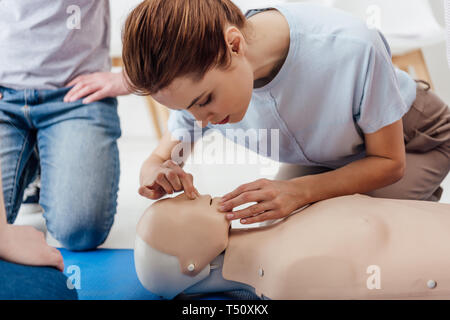 Donna pratica tecnica di esecuzione della rianimazione cardiopolmonare su manichino durante la formazione di primo soccorso Foto Stock