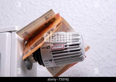 Termostato sulla scatola del radiatore con le banconote - risparmiare sui costi di riscaldamento Foto Stock
