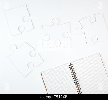 Aprire il notebook in una cella e su uno sfondo bianco, accanto al grande puzzle di vuoto, vista dall'alto Foto Stock