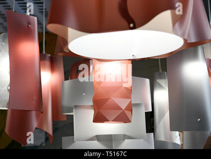 Moderni LAMPADARI in plastica di colore rosso e argento i colori con forma geometrica design e lampade incandescenti, appeso a fili bianchi. Visto da vicino da l Foto Stock