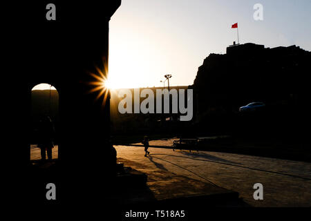 Bambino in esecuzione attraverso la piazza al tramonto contro la luce Foto Stock