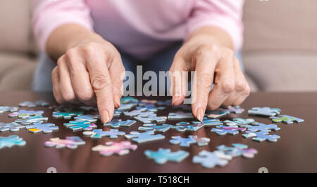 Donna anziana mani facendo puzzle closeup Foto Stock