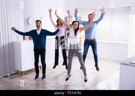 Giovani Imprenditori Jumping in Office alzando le braccia Foto Stock