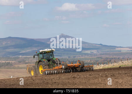 Bennachie in Rural Aberdeenshire fornisce lo sfondo per questa scena di un agricoltore la preparazione di un campo per la semina Foto Stock