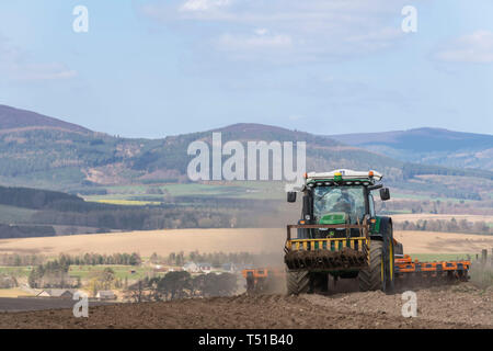 Un agricoltore straziante un recentemente arato in Aberdeenshire con Pitfichie Hill in background Foto Stock