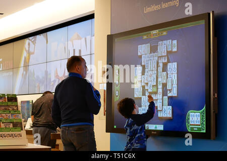 Coquitlam, BC, Canada - 31 Marzo 2019 : Moto del padre e figli giocare xbox gioco sullo schermo della TV in Microsoft Store Foto Stock