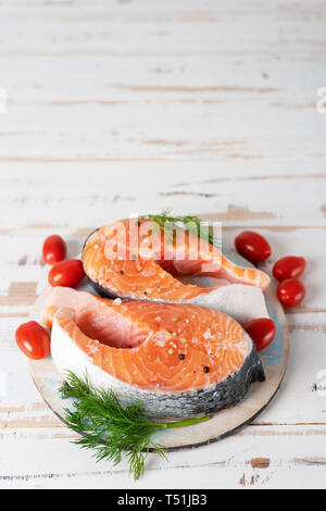 Due fresche Materie filetti di salmone con pomodori sul tavolo di legno Foto Stock