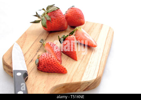 Affettare le fragole su un tagliere Foto Stock