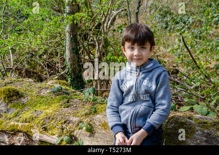 Un ragazzo giovane pone per un ritratto al di fuori di esso in una zona boscosa di campagna, Foto Stock