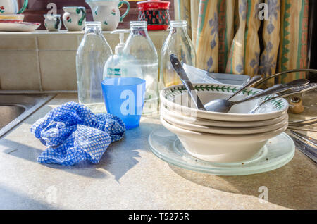 I piatti sporchi e la piastra impilati su un piano di lavoro di una cucina accanto al lavello da cucina pronta a lavare fino. Foto Stock