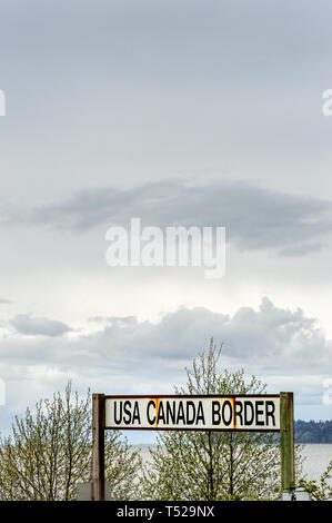 Aprile 14, 2019 - Surrey, British Columbia: Ferrovia BNRR USA Canada segno di confine e Semiamoo Bay ad ovest sotto il cielo nuvoloso. Foto Stock