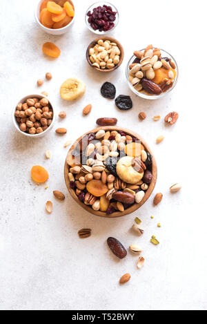 I dadi misti e frutta secca in ciotola di legno su sfondo bianco, vista dall'alto. Snack sani - mix di dadi organici e frutti secchi. Foto Stock