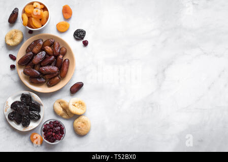 Frutta secca in ciotole su marmo bianco di sfondo, vista dall'alto, copia dello spazio. Snack sani - assortimento di organico frutta secca. Foto Stock
