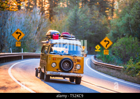 Vecchio shabby popolari come un motore mini home per viaggiare mini giallo van con ruota di scorta sulla parte anteriore caricato con attrezzature per il campeggio corse su una curva di un Foto Stock