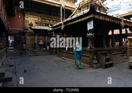 Kathmandu, Nepal - Gennaio 15, 2016: Una donna anziana nei locali del tempio d'oro a Patan a pagare il suo omaggio. Foto Stock